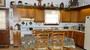 A kitchen with wooden cabinets, a dining table with floral tablecloths, and various kitchen appliances.
