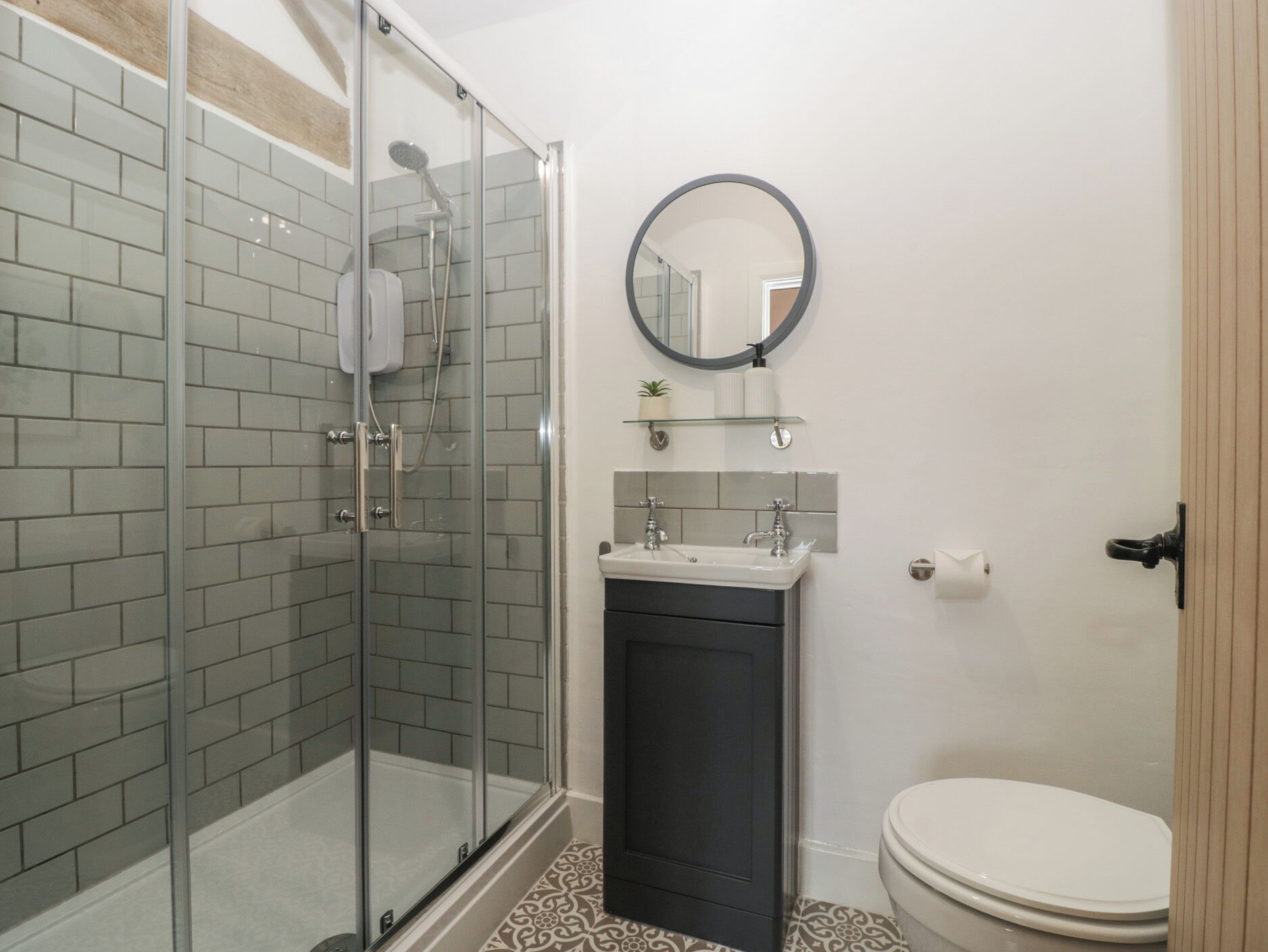 A bathroom with a glass shower enclosure, a sink, a toilet, and a mirror.