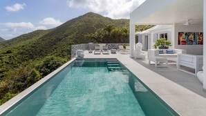 Ein moderner Poolbereich im Freien mit Blick auf eine üppige Berglandschaft.