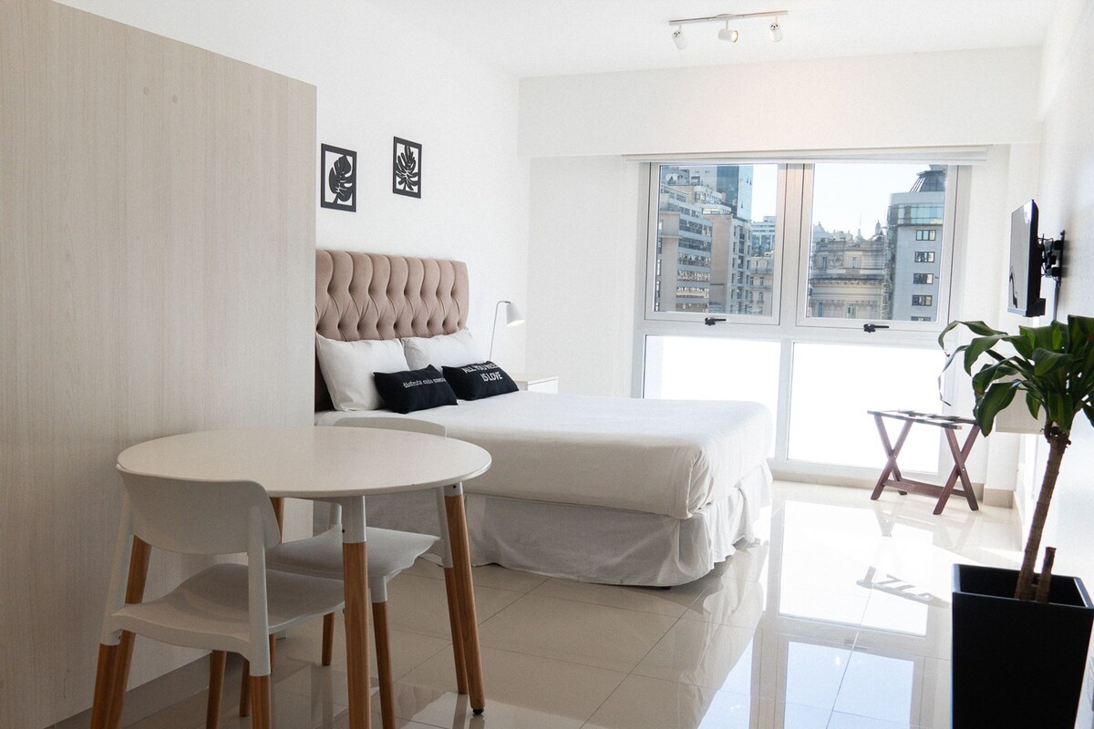 Une chambre à coucher moderne avec un lit, une petite table et une plante en pot.