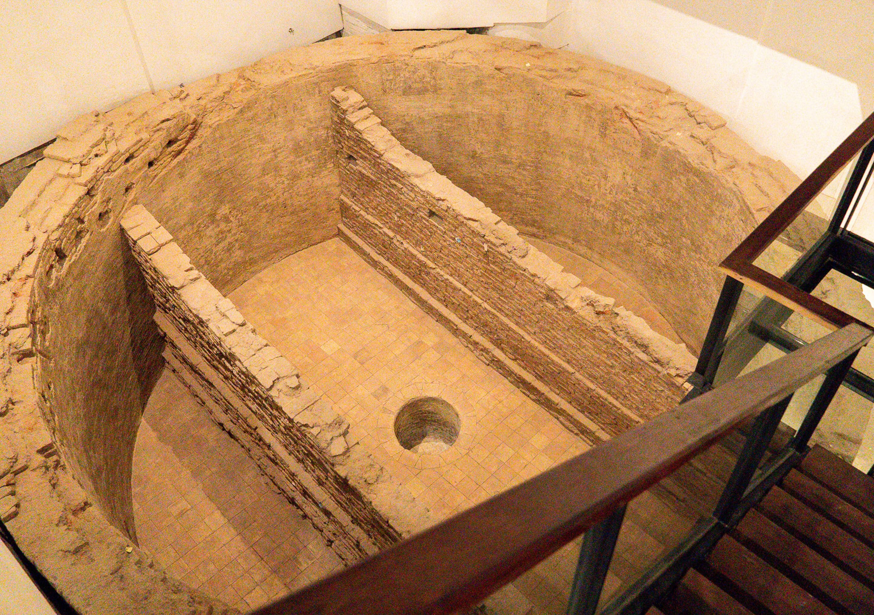 A circular stone structure with a central hole, surrounded by a wooden railing.