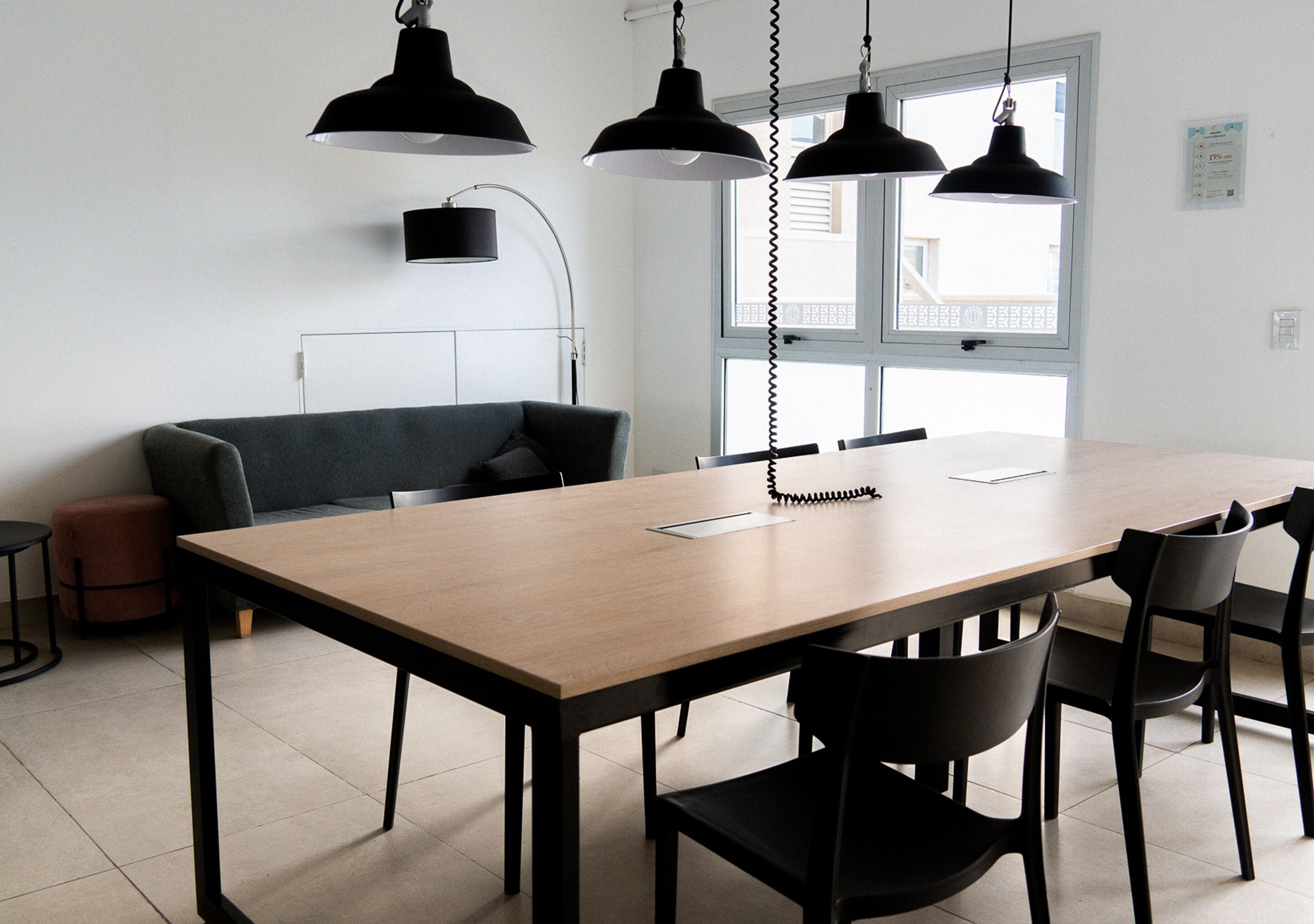 A modern dining area with a wooden table, black chairs, and pendant lights.