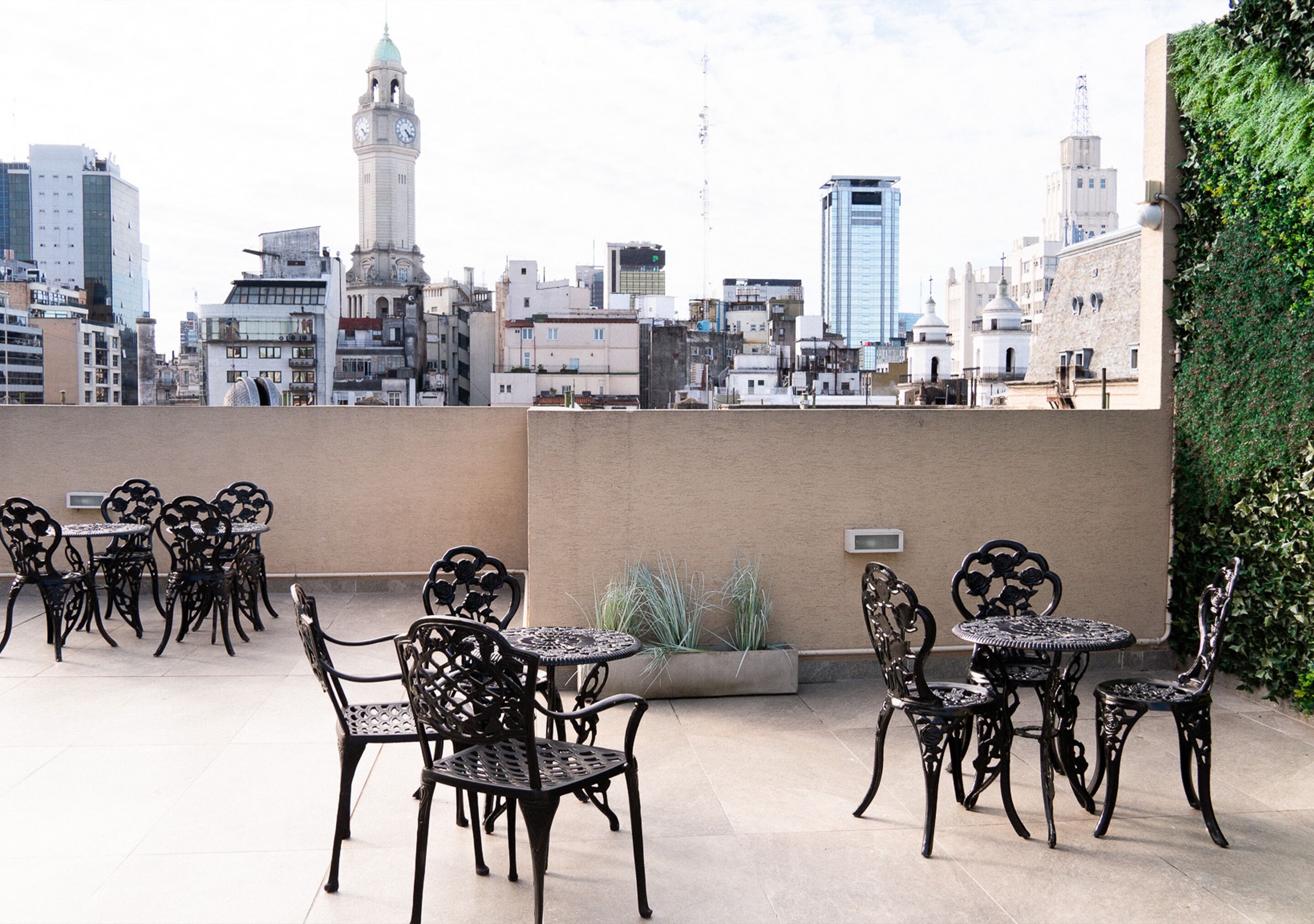 A rooftop terrace with outdoor seating, a view of the city skyline, and a clock tower in the background.