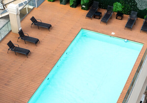 Una piscina al aire libre con sillas de descanso y un muelle de madera.