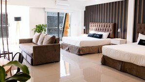 Una habitación de hotel moderna con una cama grande, un sofá, un comedor y un balcón con vistas.