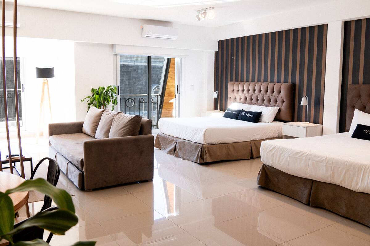 Een moderne hotelkamer met een groot bed, een zithoek, een eethoek en een balkon met uitzicht.