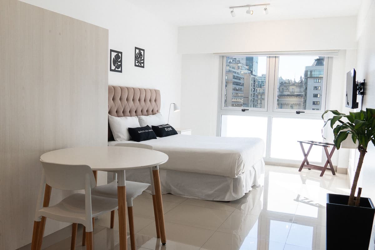 Een moderne slaapkamer met een bed, een klein tafeltje en een potplant.