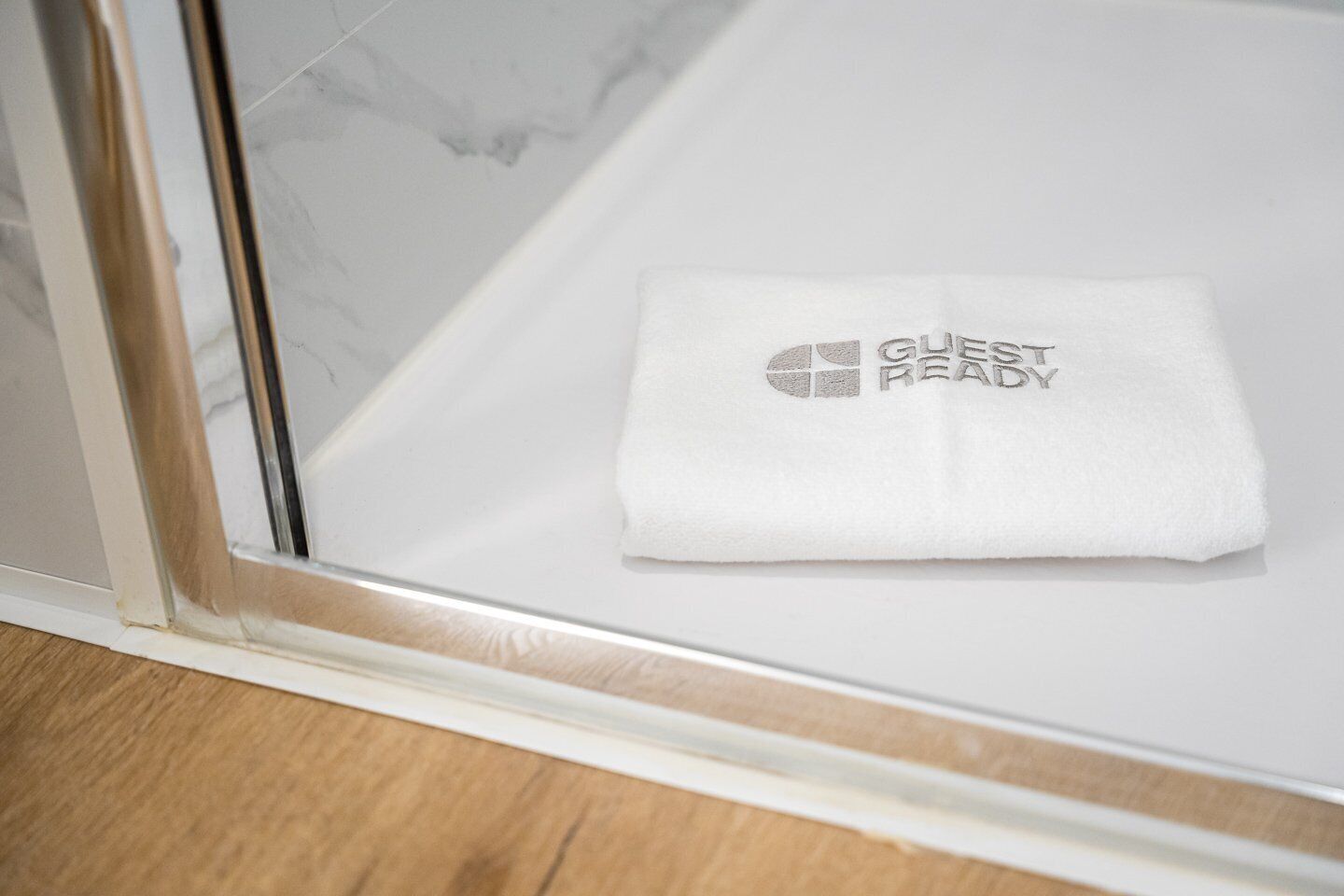 Een witte handdoek met de tekst 'GUESS READY' op een badkamermeubel.