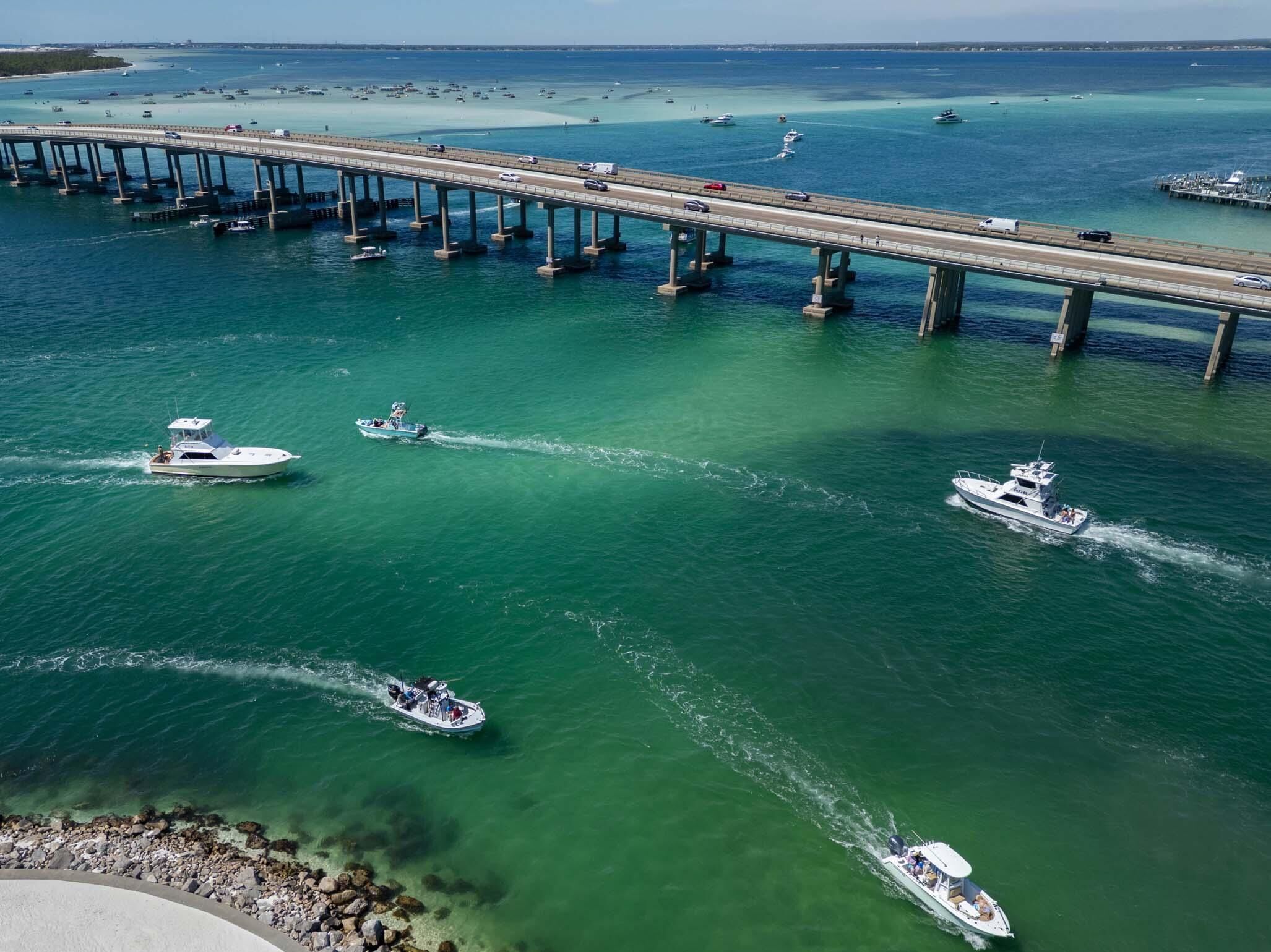 A bridge over water with boats and a clear sky.
