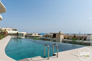 Ein moderner Pool mit klarem, blauem Wasser, umgeben von einer gefliesten Terrasse und Glasbarrieren.