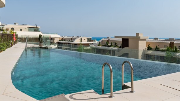 A modern swimming pool with clear blue water, surrounded by a tiled deck and glass barriers. - Valley | Sea view - pool - terrace (Fuengirola)