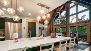 A spacious kitchen with a large island, stainless steel appliances, and pendant lighting. - !NEW! Epic Mountain Views! Arcade-Ping-Pong-Hot Tub (Sevierville)