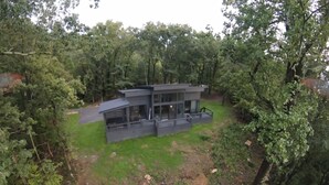 Une maison moderne à deux étages, entourée d’une forêt dense.
