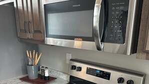 Une cuisine équipée d’un four à micro-ondes, d’un four et d’une plaque de cuisson en acier inoxydable.