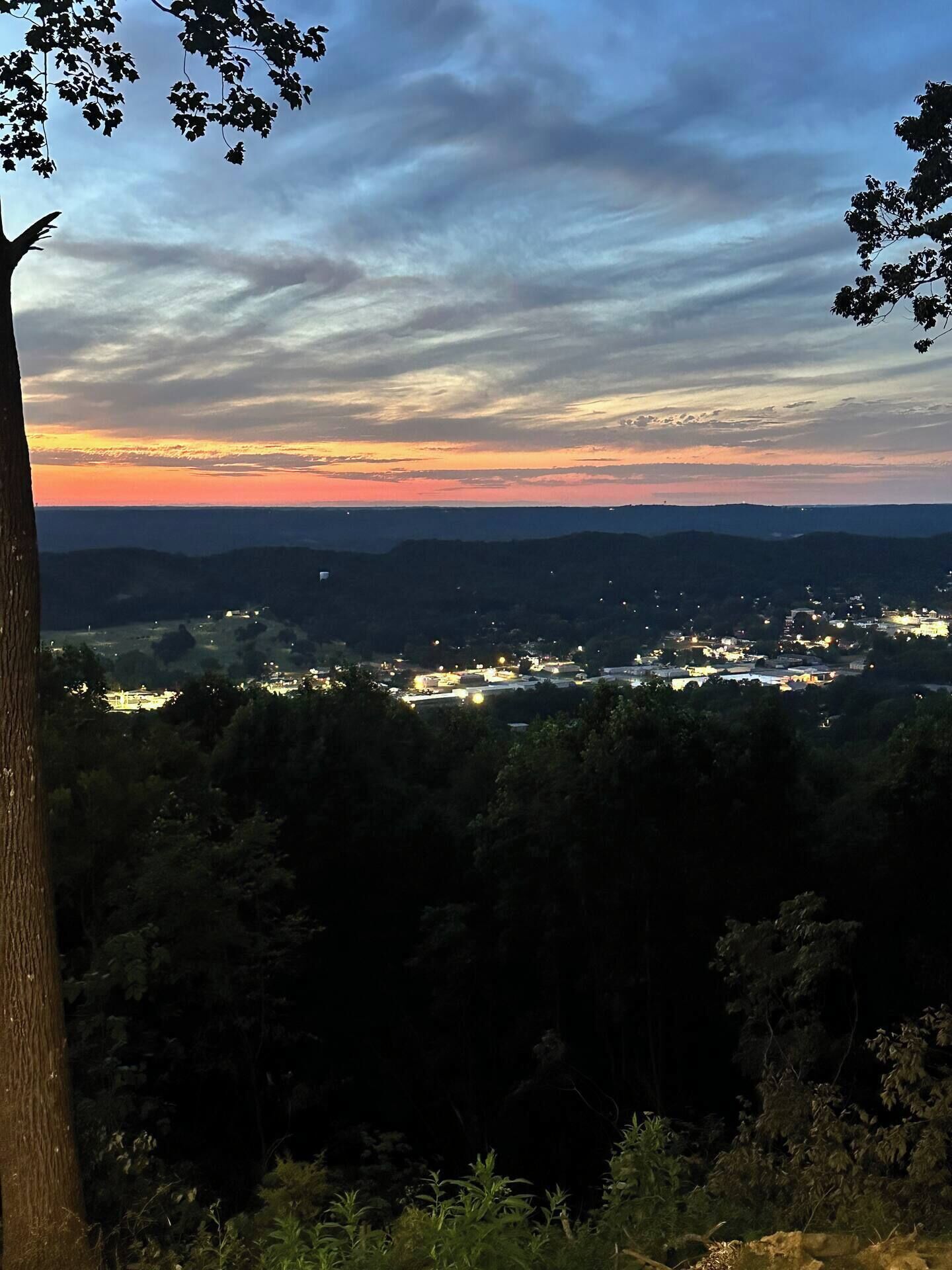 A panoramic view of a town at dusk with a clear sky and distant mountains.