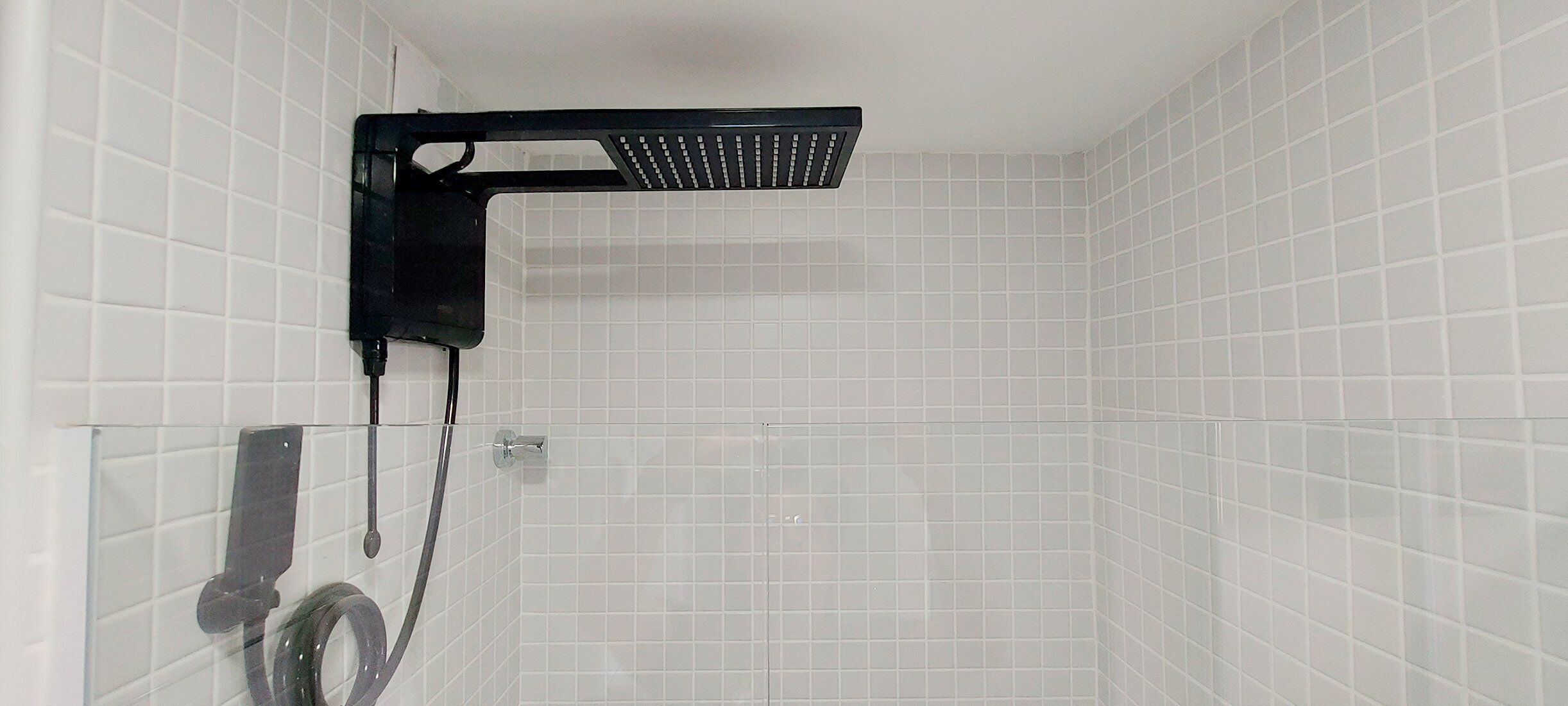 Un espace douche doté d’une pomme de douche noire et d’un flexible de douche.