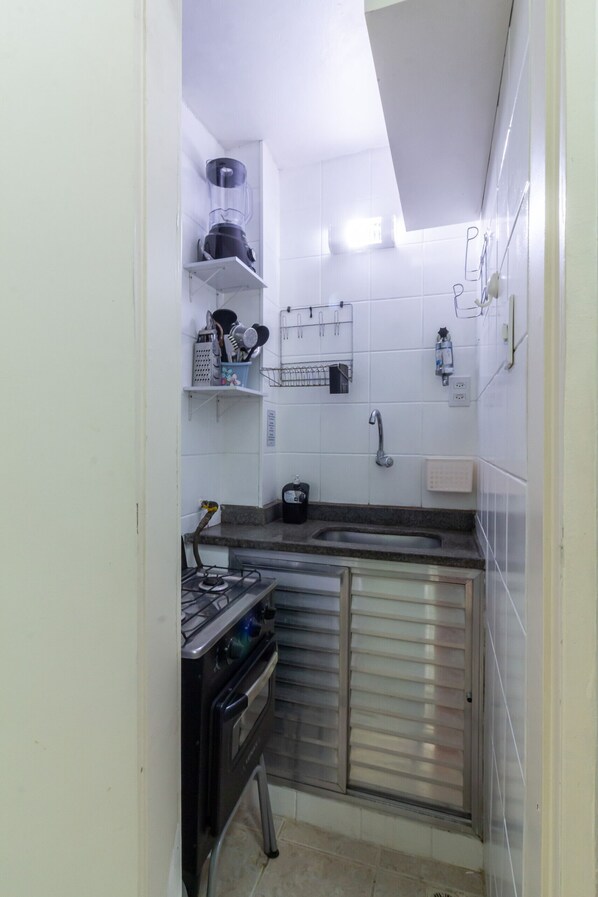 A compact kitchen with a gas stove, a sink, and a small countertop.