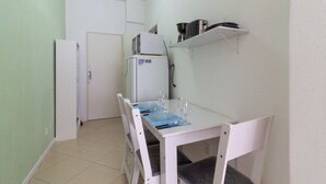 A small kitchen with a white table set for two, a microwave, a refrigerator, and a coffee maker on a shelf. - 6 Minutes From Copacabana Beach Nsc904b (Rio de Janeiro)