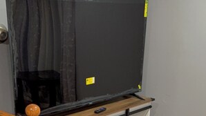 A wooden staircase with a TV on a white cabinet with sliding doors.
