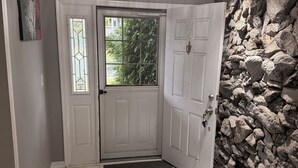 A clean, modern entryway with a white door, a stone wall, and a chandelier.