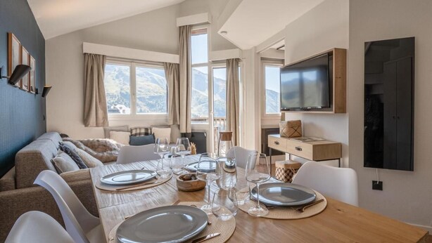 A modern dining area with a wooden table set for four, a sofa, and a TV mounted on the wall. - 50m from resort center, 6th floor, view panoramic/resort, tv, 38m², Avoriaz (Avoriaz)