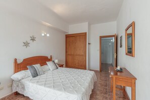 A bedroom with a wooden bed, a bedside table, a mirror, and a wardrobe.