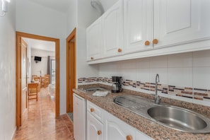 A kitchen with white cabinets, a granite countertop, a stainless steel sink, and a coffee maker.