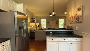 Una cocina amplia con armarios blancos, un refrigerador de acero inoxidable y una isla de encimera negra.