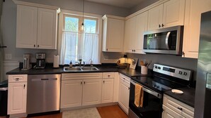 Una cocina moderna con armarios blancos, electrodomésticos de acero inoxidable y suelo de madera.