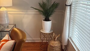 Una habitación acogedora con un sillón de cuero, una mesita con lámpara, una planta en maceta y cuadros en la pared.