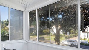 Una habitación con un ventanal grande que da a la calle, una silla y un radiador.