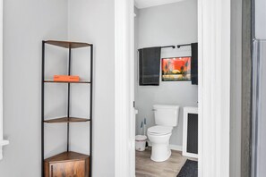 Ein Badezimmer mit Toilette, schwarzem Handtuchhalter und einem Regal mit Holzunterbau.