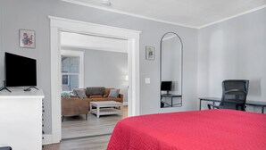 Un dormitorio moderno con una cama grande, un escritorio, una silla y un televisor.