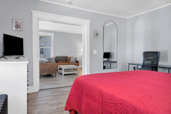 Een moderne slaapkamer met een groot bed, een bureau, een stoel en een televisie.