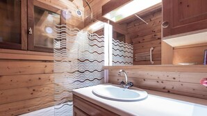 A wooden cabin bathroom with a sink, mirror, and wooden cabinets.