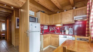 A compact kitchen with wooden cabinets, a white refrigerator, a microwave, a coffee maker, and a dishwasher.