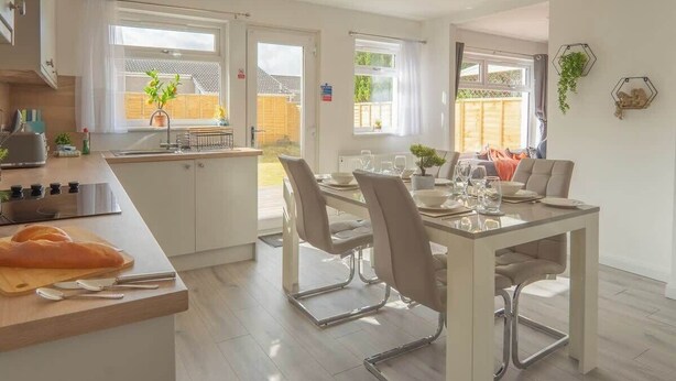 A modern kitchen with a dining area, large windows, and a view of the outdoors. - Etive House - 3 bedroom stylish home (Condorrat)