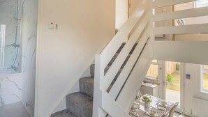 A staircase with white railings leading to a dining area with a table set for two. - Etive House - 3 bedroom stylish home (Condorrat)