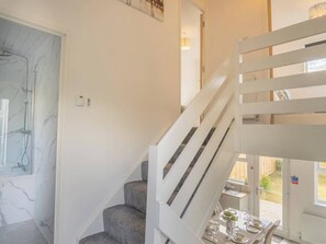 A staircase with white railings leading to a dining area with a table set for two.