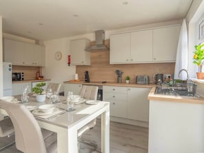 A modern kitchen with white cabinetry, a dining table set for four, and a small island with a sink.