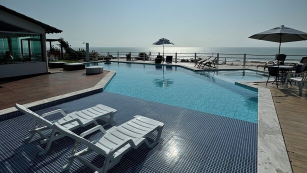 A clear blue sky, a swimming pool with tiled flooring, and lounge chairs. - Alto do Cunhaú House (Canguaretama)