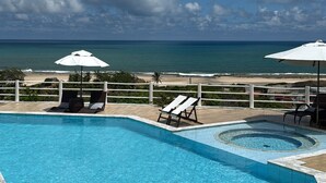 A pool area with lounge chairs and umbrellas, overlooking a beach and ocean. - Alto do Cunhaú House (Canguaretama)