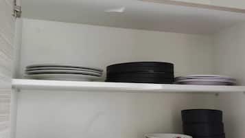 A kitchen cabinet with shelves holding stacked plates and bowls.