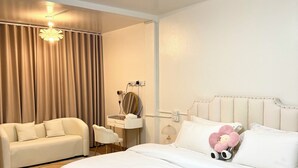 Une chambre d’hôtel avec un grand lit, un canapé, un bureau et un lustre.