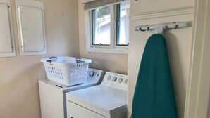 Ein kleiner Waschbereich mit Waschmaschine, Trockner und einem Fenster über dem Trockner.