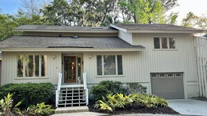 Ein zweistöckiges Haus mit Veranda, Garage und gepflegtem Garten.