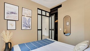 A neatly arranged bedroom with a bed, a bedside table with a vase, and framed artwork on the wall. - Lovely Apartment - 1br/4p - Buttes-chaumont (Paris)
