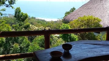 Uma mesa de madeira com uma tigela, com vista para uma paisagem exuberante e o oceano.
