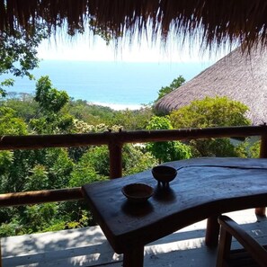 A wooden table with a bowl on it, overlooking a lush landscape and the ocean. - Zazil Retreat (Santa María Tonameca)