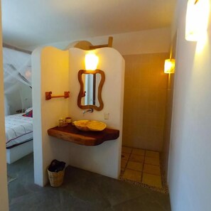 A bathroom with a wooden vanity, a mirror, and a light fixture. - Zazil Retreat (Santa María Tonameca)